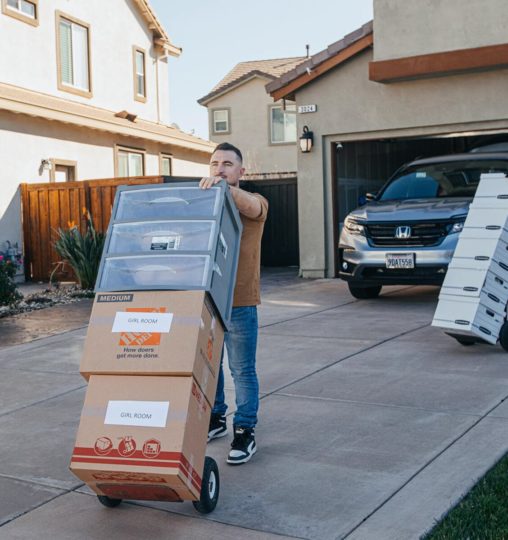 Smoove mover moving stacked boxes on a hand truck outside a home