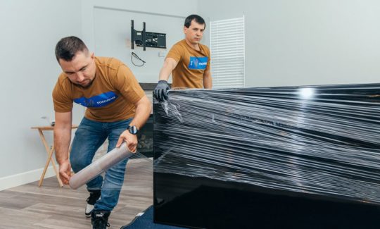 Smoove movers wrapping a large flat item in stretch wrap